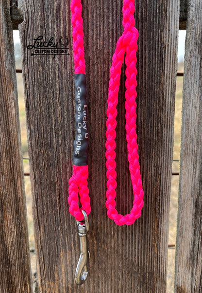 Pink dog leash with a silver snap on a wooden background