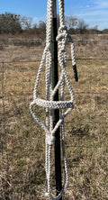 Mule Tape halter hanging on a fence post with a rural landscape in the background


