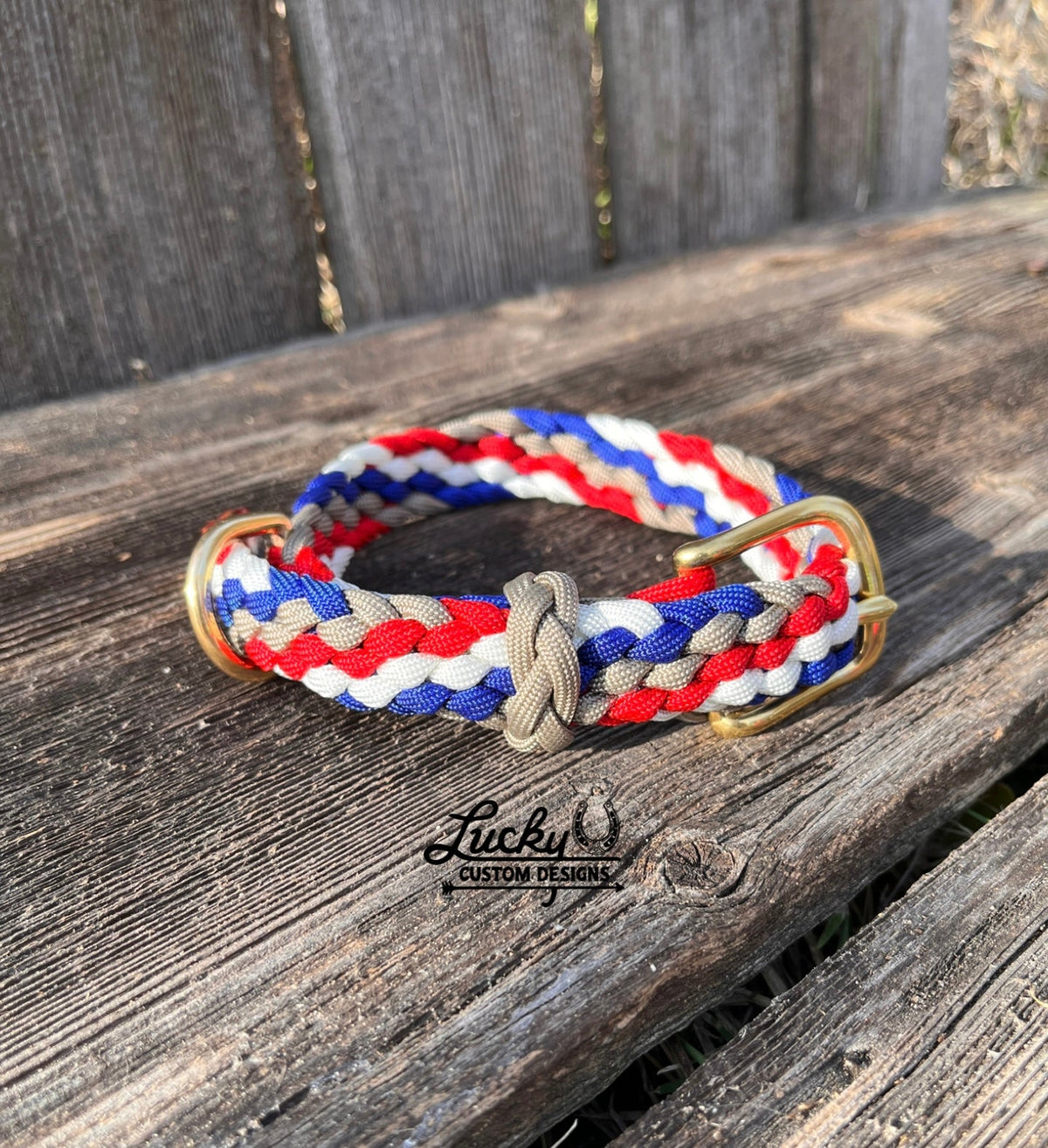 Paracord dog collar with red, white, and blue stripes on a wooden surface, featuring the Lucky U Custom Designs logo.