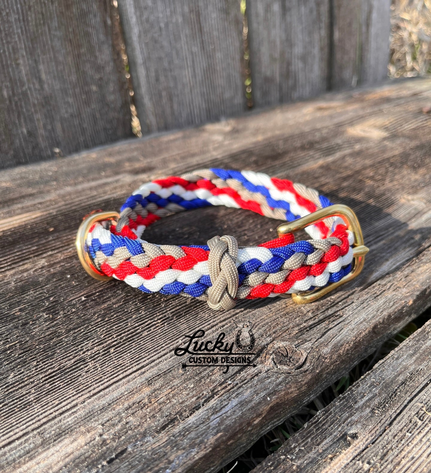 Paracord dog collar with red, white, and blue stripes on a wooden surface, featuring the Lucky U Custom Designs logo.