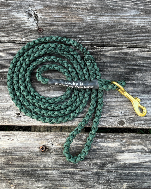 Green braided dog leash with a brass clip on a wooden surface, branded 'Lucky U Custom Designs'.