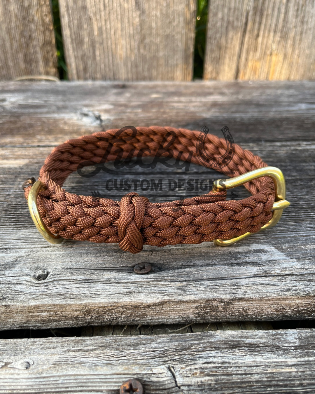 Brown paracord braided dog collar with brass hardware on a wooden surface, branded with Lucky U Custom Designs